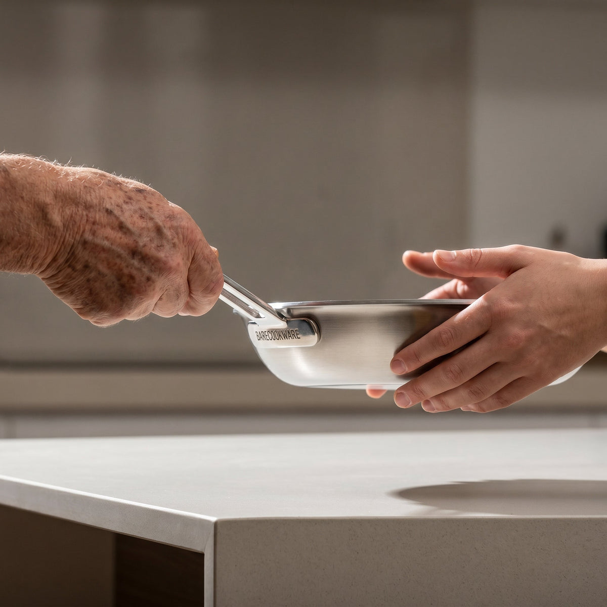 Two pairs of hands holding Everpan in a kitchen
