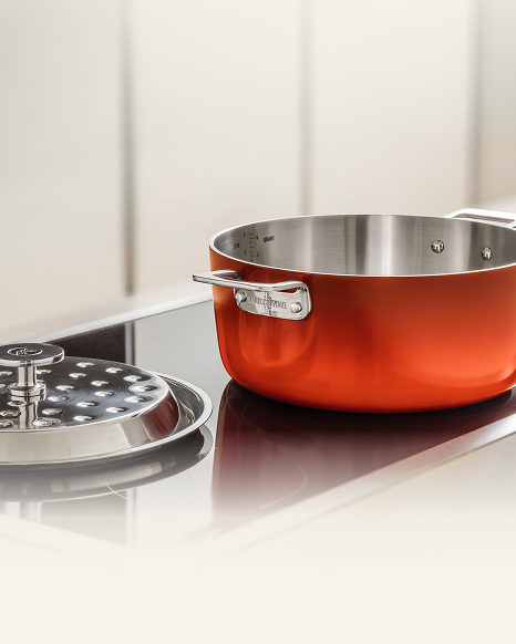 Red Dutch oven on a cooktop with its lid beside it